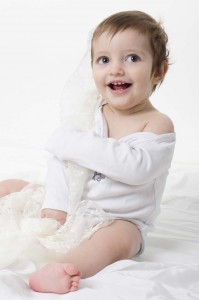 Zahira bebé de un año posando feliz con telas blancas