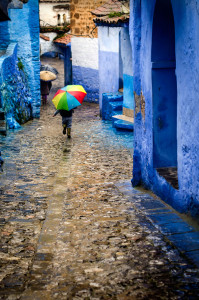 Niño con paraguas de colores en las calles azules de Chaoeun, Marruecos