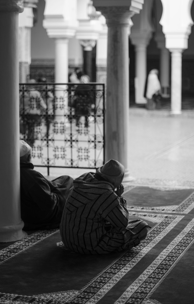 Señores sentados en templo en Fez, de espaldas, en blanco y negro. Milena Martínez, fotógrafa en Madrid.